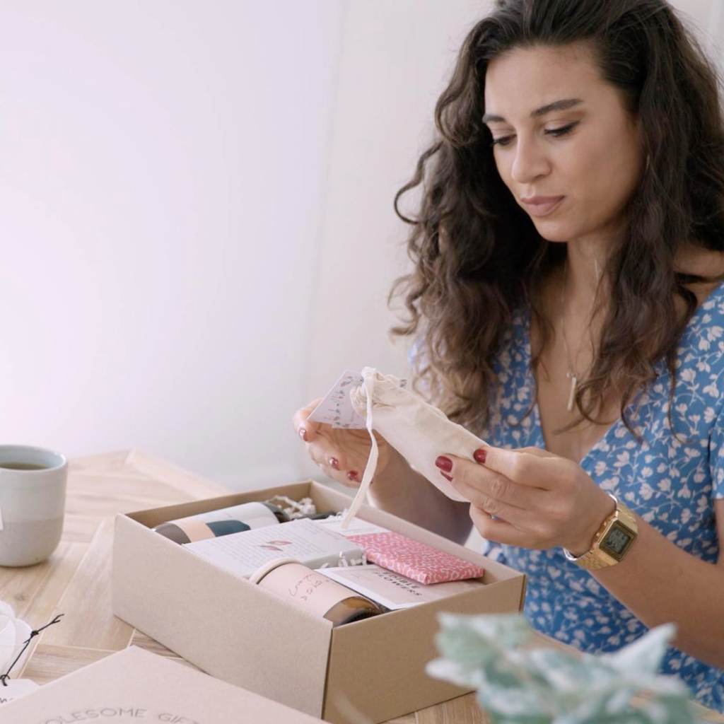 woman opening a gift box filled with natural and eco friendly products.